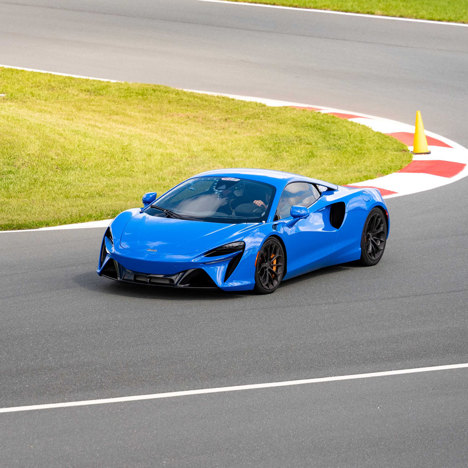 A blue supercar taking a corner on the racetrack at Circuit Florida.
