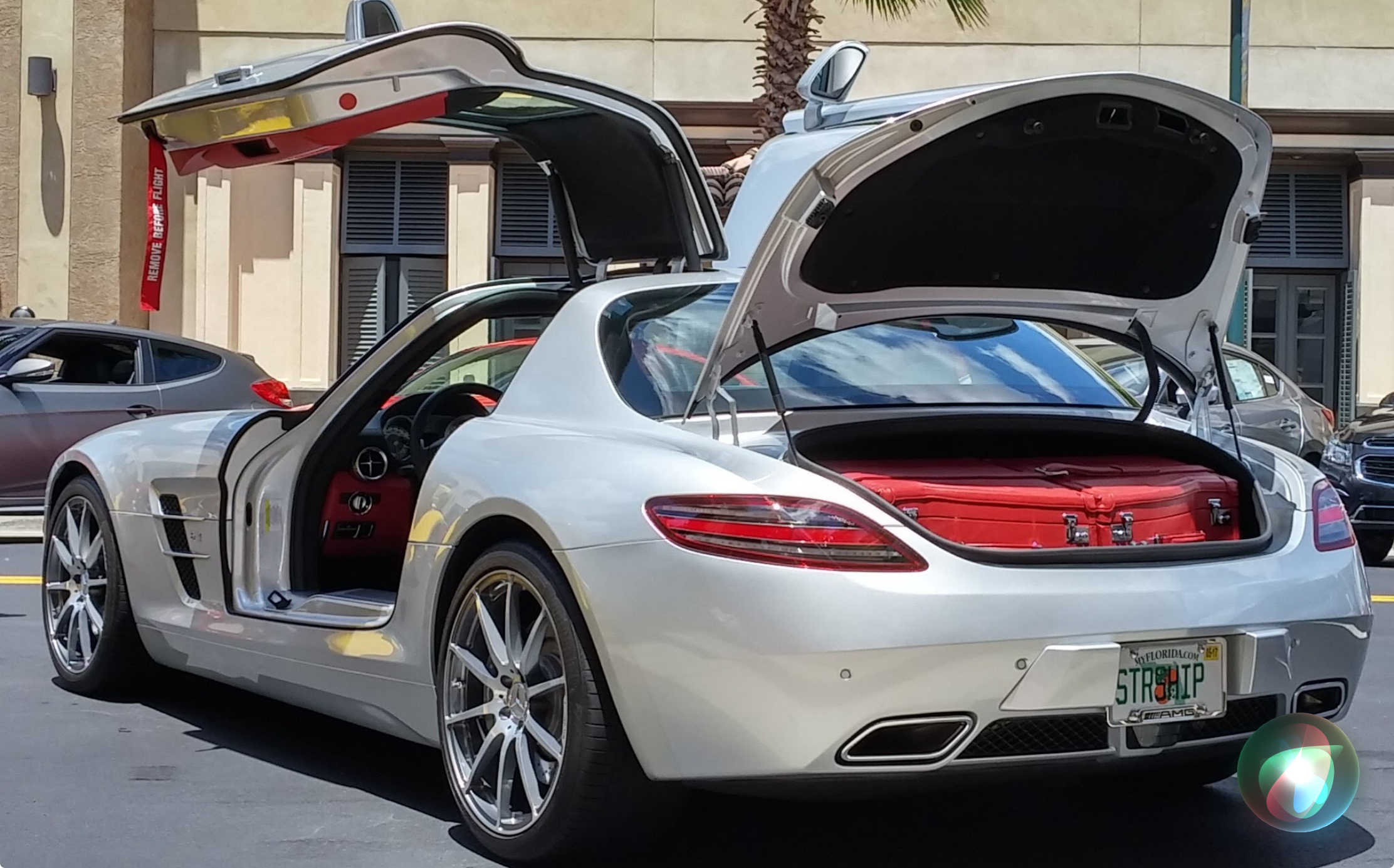 A silver Mercedes-Benz SLS AMG with its gullwing doors raised on a downtown street at the 2025 Lake Mirror Classic Downtown Car Show, Lakeland, Florida.
