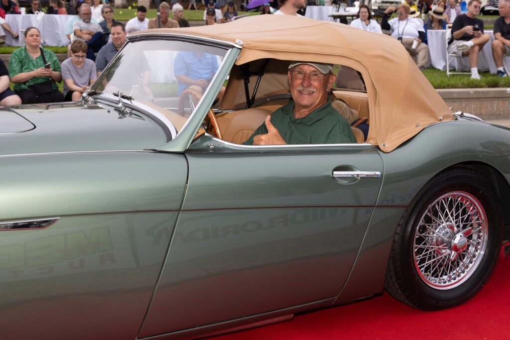 A smiling driver in a green convertible