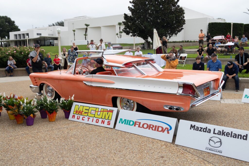A coral convertible with tail fins and whitewall tires
